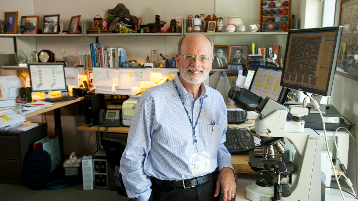 Barton Haynes in his office standing by an digital microscope
