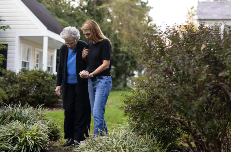 elderly mother and daughter walking through garden